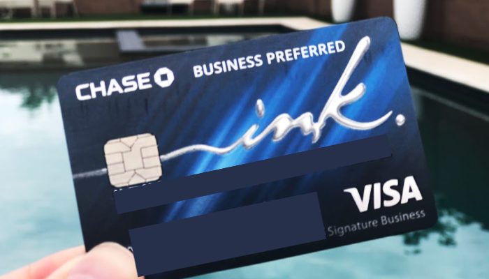a hand holding a Chase Ink Business Preferred credit card with a pool in the background