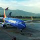a southwest airlines boeing 737 parked at a gate in costa rica with an avianca airliner taking off behind it and a united airlines plane taxing on the tarmac