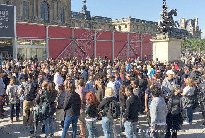 a line of people waiting to get into the Louvre museum